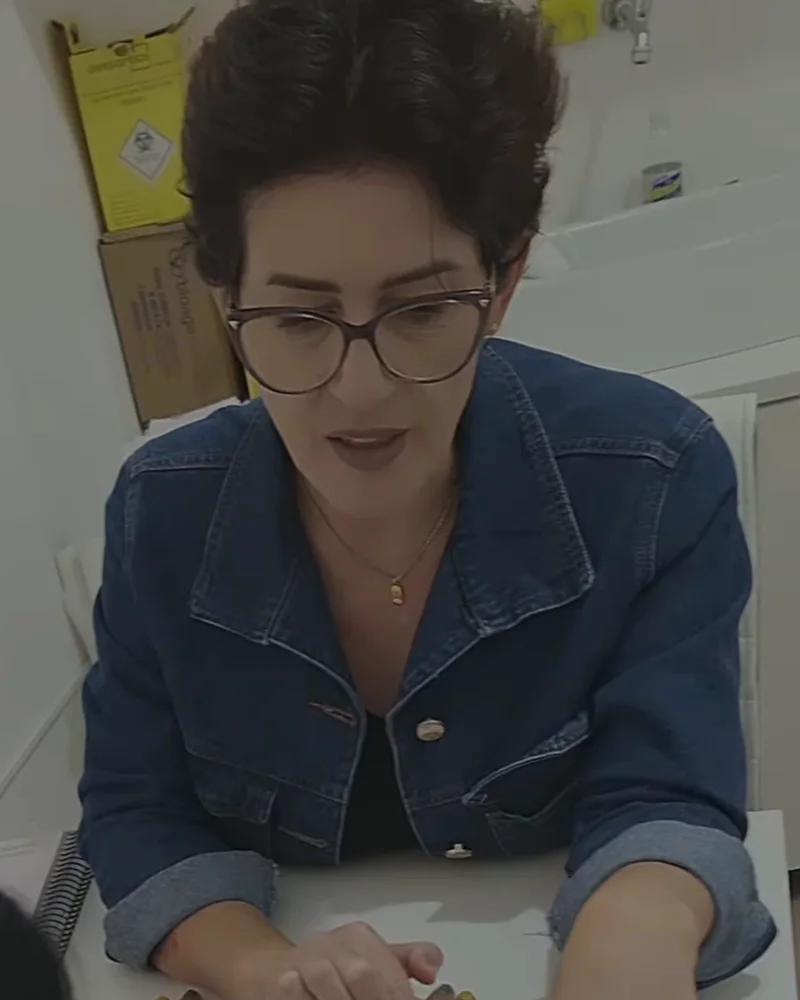 Andreia Mantovaneli, técnica em estética da Viver Bella, de óculos e camisa jeans, na mesa de avaliação da clínica